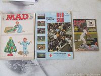 Three vintage publications laid out on a table: Mad Magazine, 1973 Red Sox program, Baseball Digest magazine.