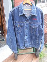 Full view of blue denim button-up jacket with collar and chest pockets, showing general condition and design.