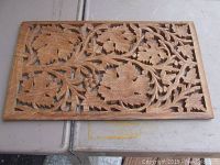 Front view of the walnut trivet showing intricate grapevine carving with leaves and grape clusters.