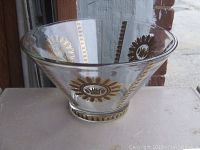 Front view of the clear glass bowl with gold floral and geometric detailing around the bowl showing the shape and design.