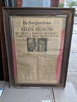 Front view of the framed vintage New York Times newspaper headline "Nixon Resigns" with images of Richard Nixon and Gerald Ford under glass in a brown art deco frame.