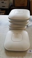 Stack of five white Cisco Aironet wireless access points showing top view and Cisco logo.