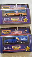 Photo showing two Matchbox collectible star car buses in original sealed packaging, one I Dream of Jeannie themed with orange and cream colors, and one Bewitched themed with blue color.