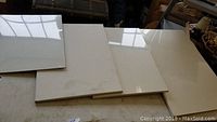 Four white artist canvases laid out on a flat surface, three wrapped in plastic and one unwrapped.