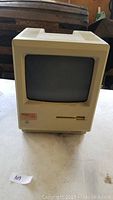 Front view of the Macintosh computer showing the small CRT screen and floppy disk drive.