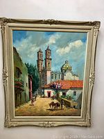 Full frontal view of the framed oil painting showing Mexican street scene with church towers and dome
