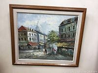 Framed original oil painting signed Burnett showing street scene with buildings and people.