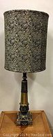 Full lamp view showing tall brass column with paisley fabric shade on top.