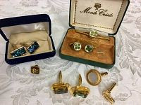 Full lot showing several cuff links and tie clips displayed on a table including the Monte Cristo boxed set