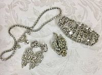 Overview photo of the vintage rhinestone jewelry lot showing necklace, earrings, brooch, and bracelet on a white patterned fabric background.