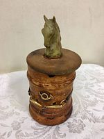 Full view of the leather-covered cylindrical humidor with horse-head topped wooden lid and decorative brass elements on the body.