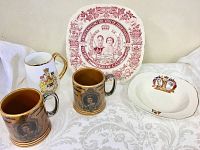 Overall group of five vintage royalty dishes including two brown portrait mugs, one white gold-trimmed mug, one white gold-rimmed plate, and one commemorative square plate.