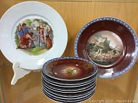 Photo of eleven decorative plates, showing two large 9.5-inch plates and a stack of nine smaller plates with ornate designs and patterns.