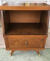 Front view of the nightstand showing the open compartment and single drawer with brass pull.