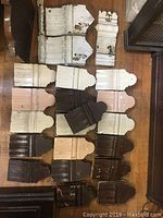 Multiple small to medium sized solid wood decorative architectural corbels and brackets in white, cream, dark brown, and natural wood tones; showing fluted and carved detailing, some with chipped paint and wear.