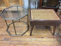 Wide shot showing both brass-coated octagonal glass side table and wooden cane-top stool with storage