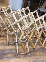 Four foldable wooden racks placed side by side on the floor, showing two lattice expandable bottle racks and two peg-style hat racks.