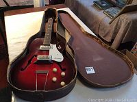 Guitar in open hard shell case showing front body and case interior