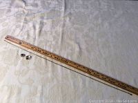 Photo showing wooden ruler measuring the chain near the two silver rings on a fabric background.
