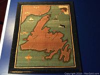 Overall front view of rectangular hooked wool mat on blue surface, showing full coastline map design and navy border