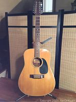 Front view of the natural-finish 12-string acoustic guitar on stand