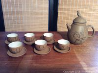 Six cups with oriental script design and matching saucers, teapot positioned right side top