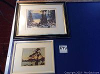 Two framed landscape prints side by side on blue table, one identified as Tom Thomson print.