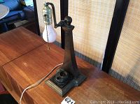 Full view of lamp showing metal base, tapered arm, pull chain bulb socket, and electrical cord.