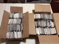 Two open boxes packed with large amounts of sorted and sleeved sports cards