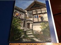 Full view of oil painting showing rustic stone and wood home with laundry hanging on balcony, signed Erica 75 at bottom right corner.