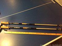 Full view of two LEKI walking sticks next to a ruler for size reference