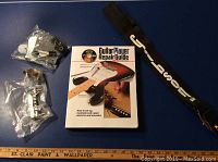 Guitar parts and accessories including mounting plates, knobs, springs, and a repair guide book arranged on a blue surface.