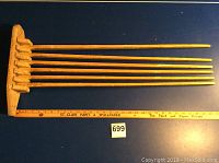 Full view of wooden wall clothes dryer showing six horizontal bars and wooden base with ruler for size reference.