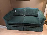 Full frontal photo of the teal blue velvet loveseat showing cushions and armrests.