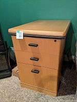 Photo of a wooden three-drawer filing unit with lock and black handles, showing all three drawers, lock detail, and overall condition.