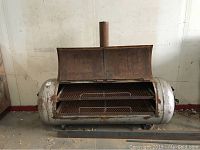 Full view of large cylindrical metal smoker showing dual opening lid with handles, mounted on base supports, with chimney on top.