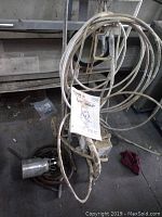 Overall view of Titan Epic 440HP airless sprayer unit with coiled hose and attached spray gun on the floor in workshop setting.