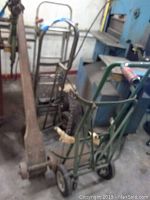Photo showing four assorted hand trucks of different styles in a workshop area.