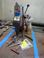 Full view of drill motor on magnetic stand, accessories, and spray bottles on bench