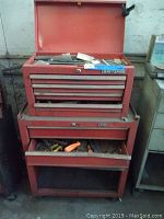 Front view of red Craftsman toolbox chest with multiple drawers, two drawers open showing assorted tools inside. Shows wear and one drawer partially open not closing.
