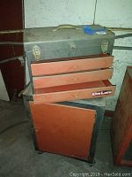 Front view of closed toolbox on top of storage chest, showing labels and handles.