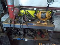 Wide view of metal shelving unit with bench grinder, die grinder, extinguisher and other power tools.