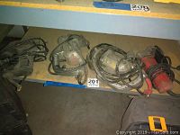 Shelf with three metal shears and one red electric jigsaw showing worn condition, cords coiled.