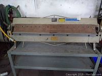 Full front view of the 48-inch brake on its stand with clamping fingers