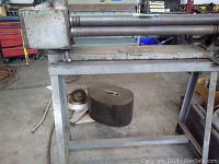 Front view of the hand roll showing two large cast iron rollers and supporting frame on steel stand