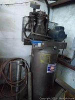 Full view of the American IMC air compressor with vertical tank, motor unit on top, and attached air dryer with coiled hoses.