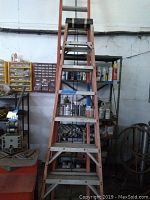 Full height view of the orange fiberglass 8-foot step ladder in a workshop.