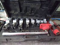 Overview of the tubing bender kit inside its black plastic storage case showing bending dies, handle, and clamp.