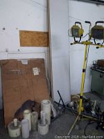 White vinyl sheets and wooden shelving leaning against wall near electrical panel and cardboard