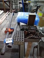 Metal sprinkler pipes with threaded ends and fittings alongside metal and cardboard boxes containing steel stamps.